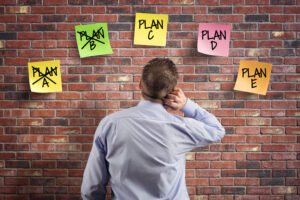 Plan A B C D and E alternative strategy planning and contingency solution, choice and decisions businessman thinking with plan options written on adhesive notes stuck to a brick wall